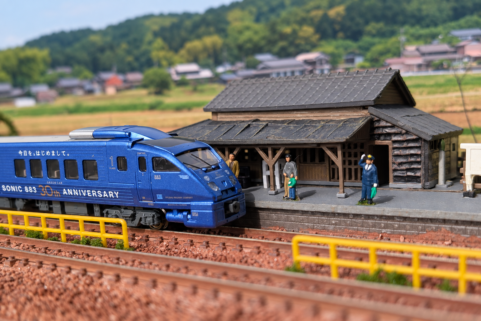 駅舎前を走る青い列車の鉄道模型